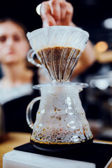 Drip coffee making with a funnel shaped filter paper on a glass vessel