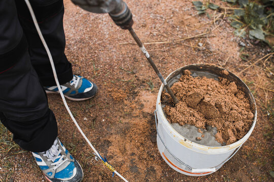 Preparation Of Cement Glue Mortar In A Bucket Of Cement And Sand Using A Mixer Nozzle On A Drill - The Work Of A Professional Bricklayer