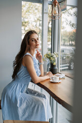 beautiful young girl posing in a coffee shop. holding a cup of coffee