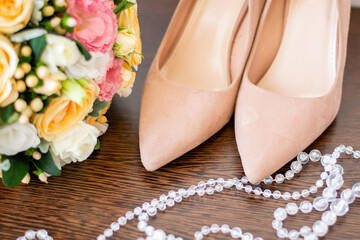 wedding bouquet of roses next to beige bride’s shoes
