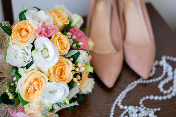 wedding bouquet of roses next to beige bride’s shoes