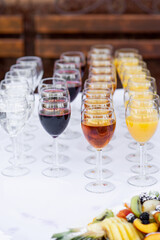 glass wine glasses filled with drinks stand in rows