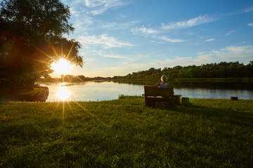Obraz premium Woman Sitting On Bench During A Beautiful Sunset