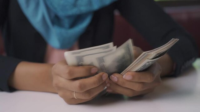 Arab woman counting dollar from work.