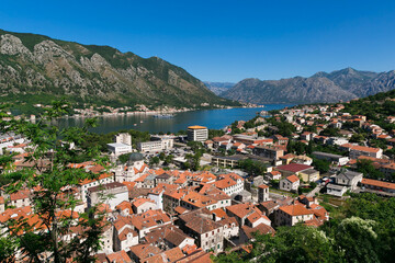 Naklejka na ściany i meble Kotor bay view in Montenegro, summer time. Kotor town. Mountains, water, red roofs of the old city below. Tourist route to the height. Observation decks on the way.