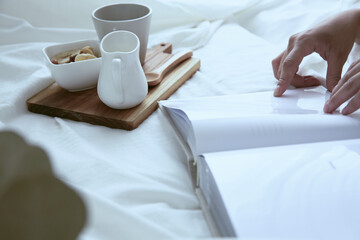 Obraz na płótnie Canvas 爽やかな朝に寝室のベッドでくつろぐ白いワンピースの女性