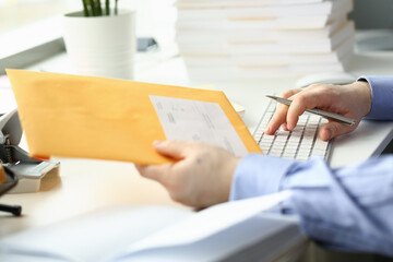 Close up top view of male hands typing on keyboard and holding folder with documents