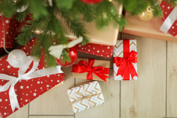 Many gifts under a festively decorated Christmas tree in a bright interior
