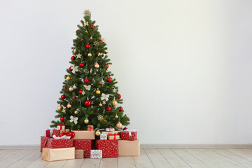 Many gifts under a festively decorated Christmas tree in a bright interior
