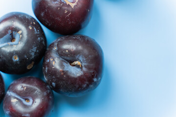 close up of fresh plums on blue background