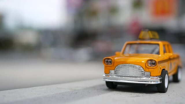 Yellow vacant mini taxi cab close up, Harmon corner, Las Vegas, USA. Small retro car model on defocused background. Little iconic auto toy as symbol of transport in soft focus. Blurred shopping mall.