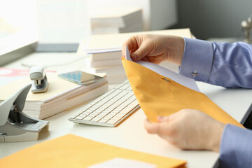 Cropped head of male hands holding pack of papers while working with computer in office