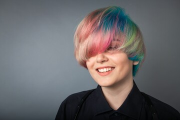 Portrait of a young woman with multi colored hair against a grey background