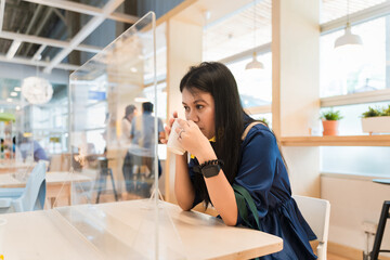 Asian women are holding cup and sitting there drinking at a restaurant or cafe with a protective...
