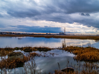 Gloomy landscape, waste recycling plant next to the lake
