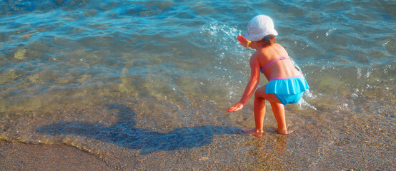 Cute little child girl having fun at the seaside. Summer vacation and healthy lifestyle concept. Horizontal image.