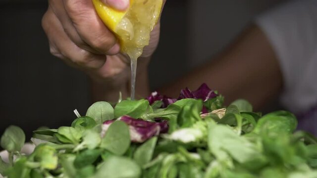 Squeezing lemon juice onto salad of  spinach and endive