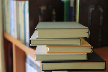 Close-up of several books stacked on the bookshelf in the library selective focus and shallow depth of field