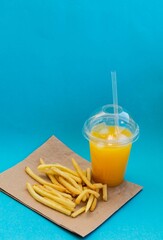 American food concept french fries and orange juice on a blue background, delicious fast food. 