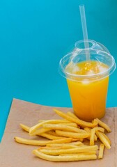 French fries and orange juice on a blue background, delicious fast food. American food concept