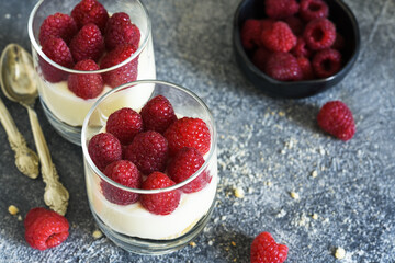 Cheesecake with raspberries in a glass on a concrete background. Classic dessert.