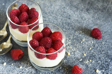 Cheesecake with raspberries in a glass on a concrete background. Classic dessert.