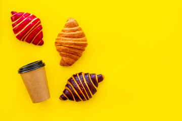 Coffee and croissants on yellow background top view