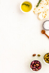 Top view of olives, olive oil, bread on white table top view copy space