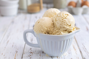 Rustic homemade creamy ice cream in ceramic cup on white wooden table
