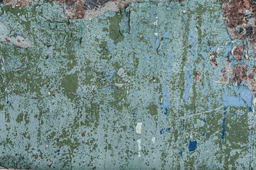 Concrete wall background with old, blue and green peeling cracked paint, atmospheric impact, outdoors.