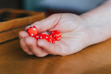 Female hand throwing  six red dices on the table. Yamb, dice game