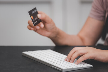 Woman is using a hand typing keyboard and uses a modern credit card by laptop or smartphone.shopping online on the card and buy order shopping online.