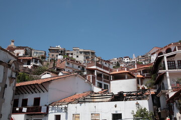 View of white and red houses with tile roofs on hill in Taxco, Mexico 
