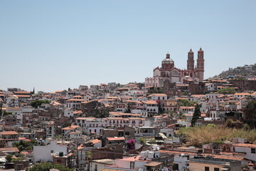 Fototapeta na wymiar View of Santa Prisca Church and dense white houses with tile roofs on the hill in Taxco, Mexico 