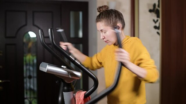 The girl trains, dries sweat with a towel and squeezes a wet towel through, then continues to workout, side view