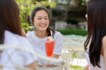 Three happy young Asian women as friends talking together at the coffee shop outdoors
