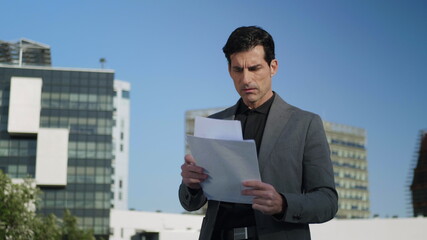 Businessman reading documents on street. Worker looking diagrams outdoors