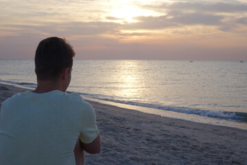 young manl on a sea beach at sunrise