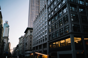 Plakat Evening view of tall building exterior with real estate for commercial and residential rent in midtown, urban architecture with high skyscrapers and old construction fronts on street in New York