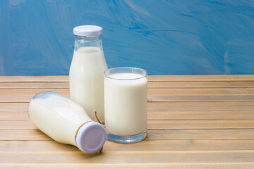 Rustic milk bottle and milk glass placed on a wooden table on a blue background Organic milk products that are delicious nutritious and healthy