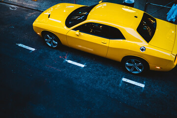 Top view of yellow powerful sport car with chromes wheels parked on asphalt road in town, bright...