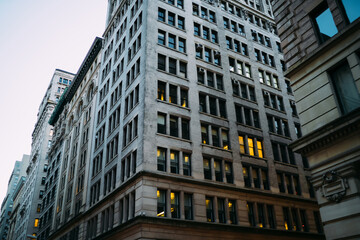 High building evening exterior with windows of rental real estate in downtown district, modern constructed architecture of megalopolis with corporate offices and residential apartments inside.