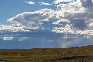 Naklejka na ściany i meble Thunderclouds lit with sunshine with the rain over polar tundra, Finnmark, Norway