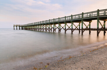 Fototapeta premium Overview of beautiful fishing pier after sunset at low tide at Walnut Beach, Milford Connecticut, USA.