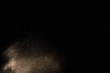 Golden colored sand splash against dark background. 