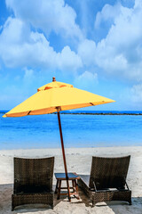 two chairs with Yellow umbrella on a sand beach