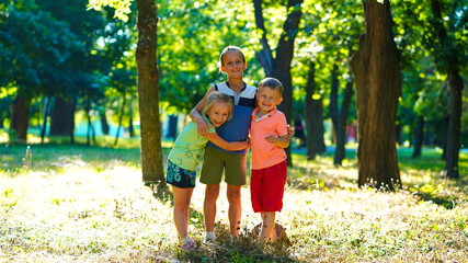 Fototapeta premium Three happy kids, little girl and two boys on lawn in the park