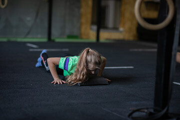 Fototapeta na wymiar Young girl in green shirt and leggings training at the gym. Copy space.