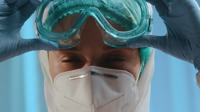 Female Doctor Or Nurse Is Preparing To Receive Patients During An Epidemic. She Puts On a Medical Mask, Goggles, a Disposable Cap, Hazmat. Health, Medicine and Pandemic Concept