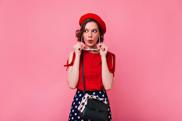 Positive white girl in cute red beret expressing interest. Indoor photo of debonair french female model with short haircut.